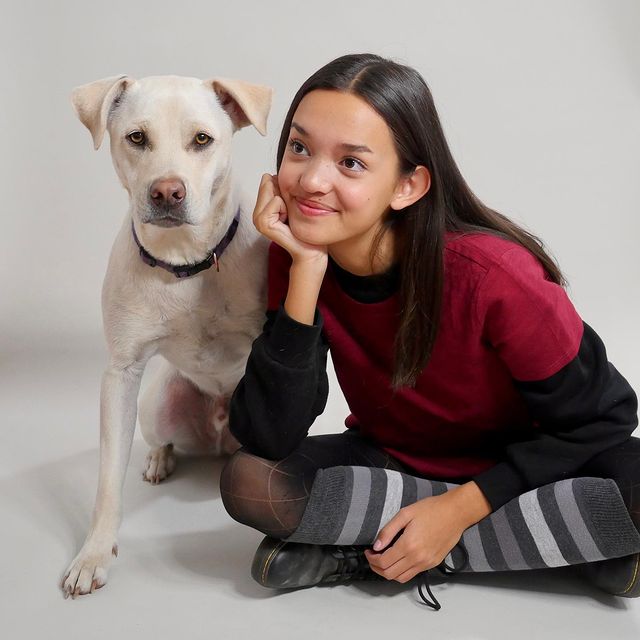 Sophia Hammons in a red and black dress posing with her pet Larry.